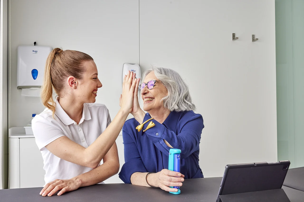 A therapist and an older woman celebrating a result together